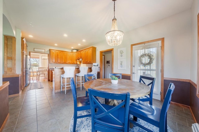 dining space with arched walkways, a notable chandelier, a baseboard radiator, and recessed lighting