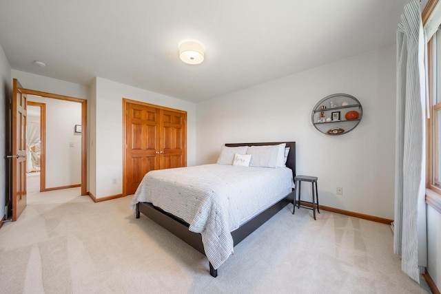 bedroom with baseboards, a closet, and light colored carpet
