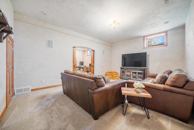 living area featuring arched walkways, visible vents, and light colored carpet