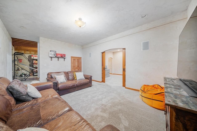carpeted living room featuring arched walkways and baseboards