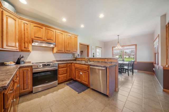 kitchen with a peninsula, a sink, under cabinet range hood, appliances with stainless steel finishes, and a chandelier