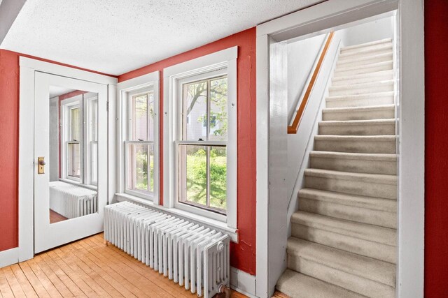 103 E Rollin St, Edgerton, WI 53534 - doorway featuring radiator heating unit, hardwood / wood-style floors, a textured ceiling, and stairway