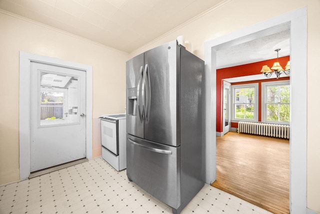 103 E Rollin St, Edgerton, WI 53534 - kitchen with radiator heating unit, stainless steel fridge, electric range, light floors, and a chandelier
