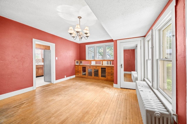 103 E Rollin St, Edgerton, WI 53534 - interior space with a textured wall, a textured ceiling, light wood finished floors, a chandelier, and baseboards