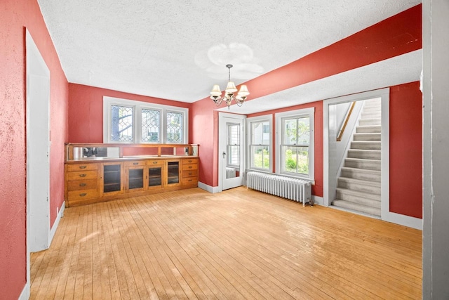 103 E Rollin St, Edgerton, WI 53534 - unfurnished dining area with radiator, a chandelier, hardwood / wood-style floors, a textured ceiling, and healthy amount of natural light