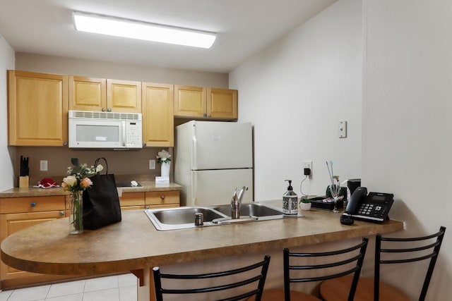 123 Center St Unit 301, Lake Geneva, WI 53147 - kitchen with light brown cabinets, a breakfast bar, white appliances, a sink, and a peninsula