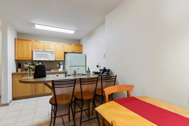 123 Center St Unit 301, Lake Geneva, WI 53147 - kitchen with a sink, a peninsula, white appliances, a kitchen bar, and light tile patterned floors