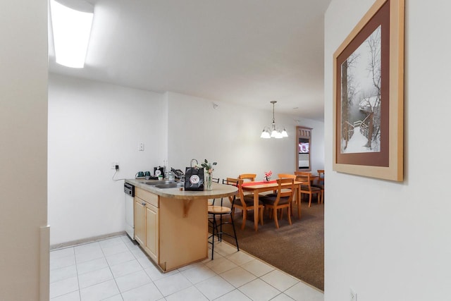 123 Center St Unit 301, Lake Geneva, WI 53147 - kitchen with white dishwasher, a notable chandelier, a sink, a kitchen breakfast bar, and light countertops