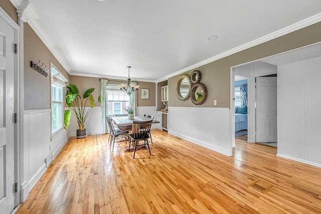 201 N Hillside Ter, Madison, WI 53705 - dining space featuring light wood-type flooring, a chandelier, crown molding, a wainscoted wall, and baseboards