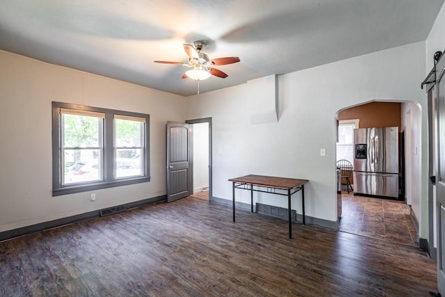 unfurnished room with a ceiling fan, visible vents, baseboards, dark wood-style flooring, and arched walkways