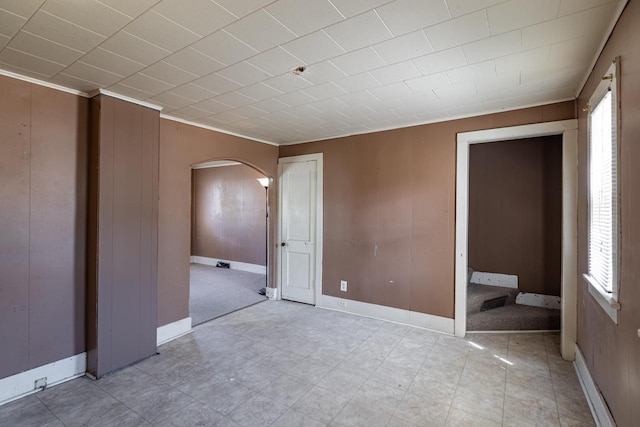 unfurnished bedroom featuring arched walkways, multiple windows, and baseboards