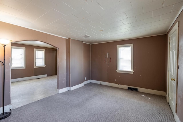 empty room featuring light colored carpet, crown molding, baseboards, and visible vents