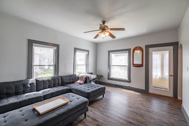 living area featuring baseboards, visible vents, ceiling fan, and wood finished floors