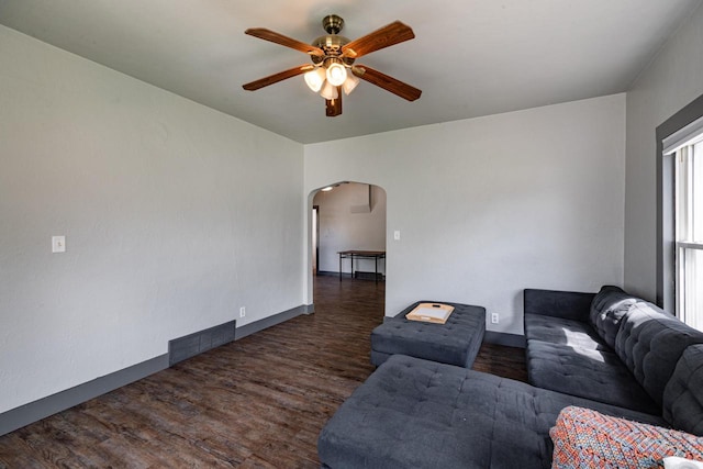 living room with wood finished floors, visible vents, baseboards, ceiling fan, and arched walkways