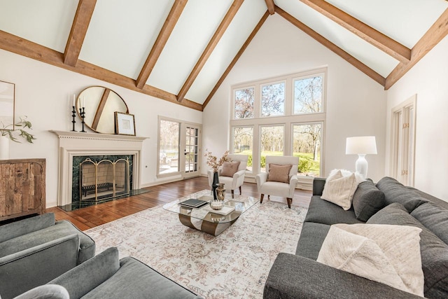 living area with high vaulted ceiling, beam ceiling, wood finished floors, and a high end fireplace