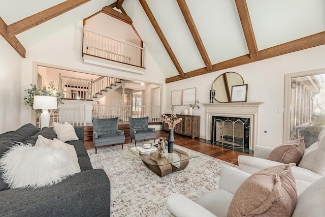 living area featuring stairs, high vaulted ceiling, wood finished floors, beamed ceiling, and a high end fireplace