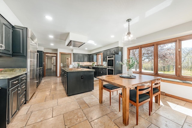 kitchen with stone tile floors, a kitchen island, dark cabinets, and recessed lighting