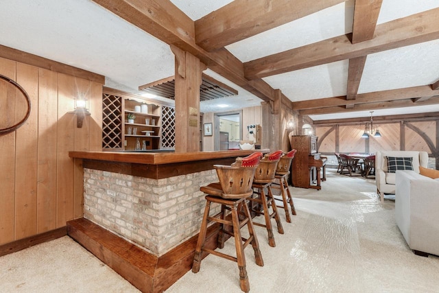 indoor dry bar featuring wood walls, carpet, and beamed ceiling