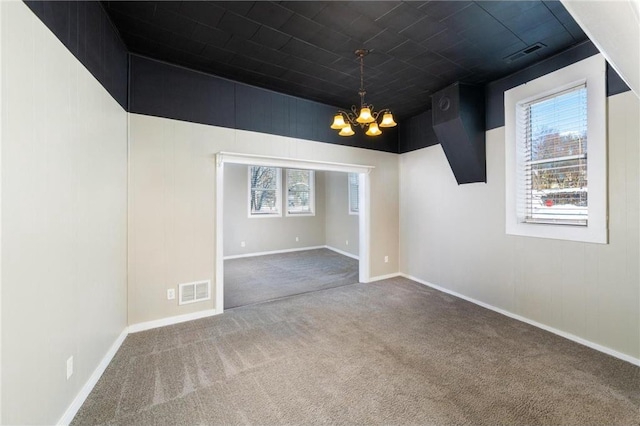 spare room featuring carpet flooring, a notable chandelier, baseboards, and visible vents