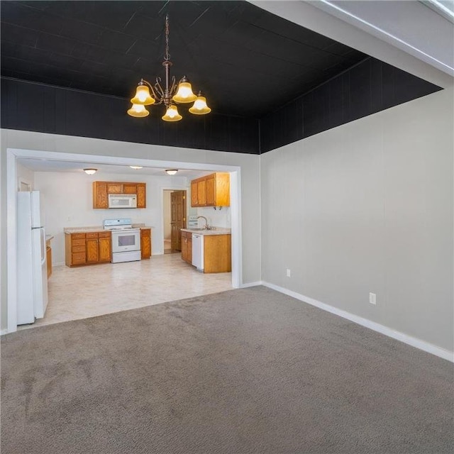 unfurnished living room with baseboards, light carpet, a chandelier, and a sink