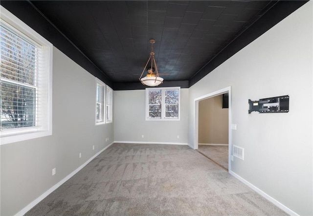 empty room featuring carpet, visible vents, and baseboards