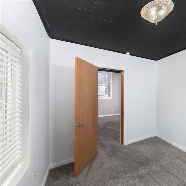 spare room featuring carpet and baseboards