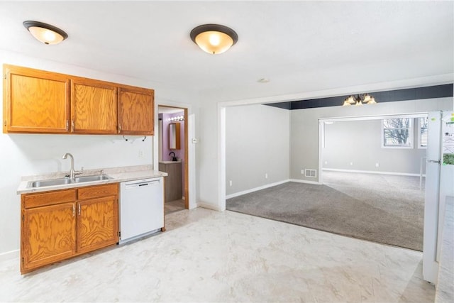kitchen with light countertops, a sink, brown cabinetry, baseboards, and dishwasher