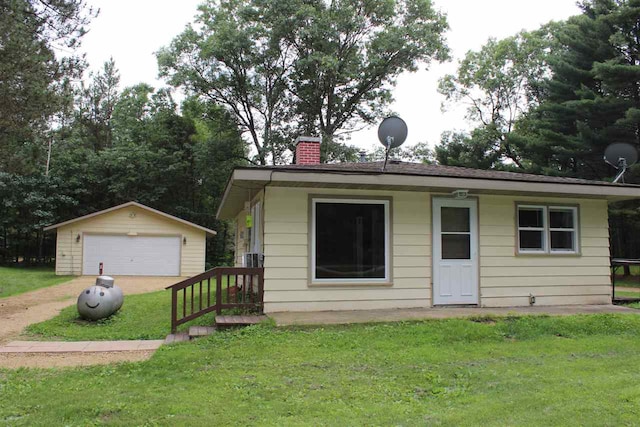 view of front facade with a detached garage, a front lawn, a chimney, and an outdoor structure