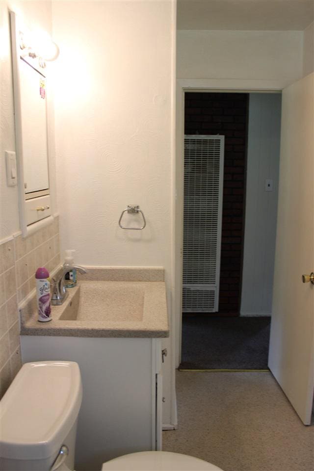 half bathroom with a sink, toilet, and a heating unit