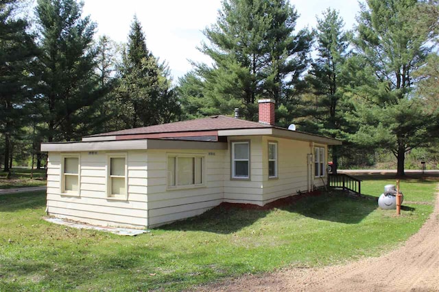 view of home's exterior featuring a chimney and a lawn