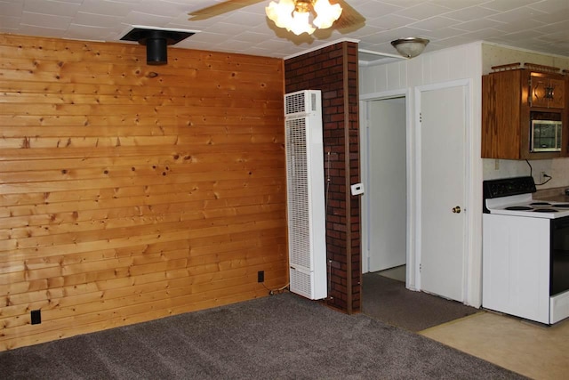 interior space with wooden walls, carpet flooring, a ceiling fan, and a heating unit