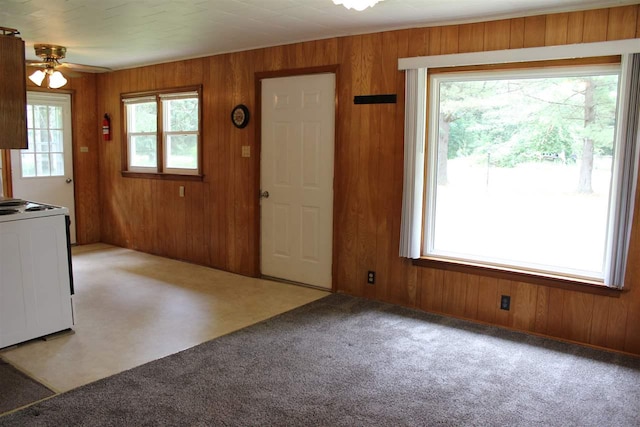 carpeted entrance foyer featuring wooden walls and a ceiling fan