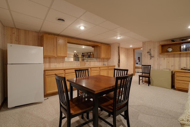 dining area featuring light colored carpet, wood walls, visible vents, and a drop ceiling