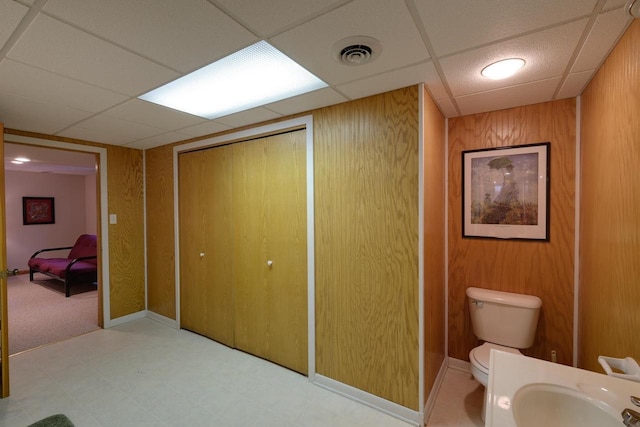 bathroom with a sink, toilet, visible vents, tile patterned floors, and a drop ceiling