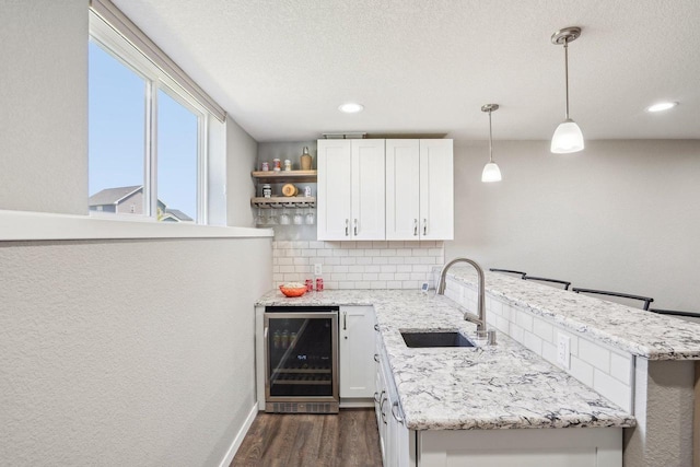 521 Dragon Willow Ln, Middleton, WI 53562 - kitchen featuring beverage cooler, a sink, a peninsula, dark wood-style floors, and white cabinetry