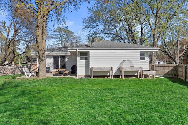 back of property featuring a fenced backyard, a patio area, a shingled roof, and a yard
