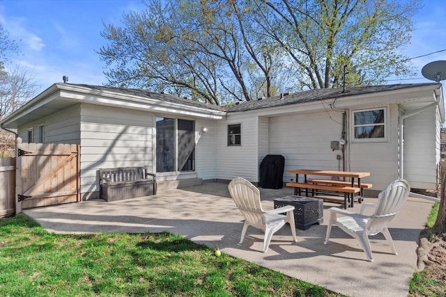 back of property with a gate, an outdoor fire pit, and a patio
