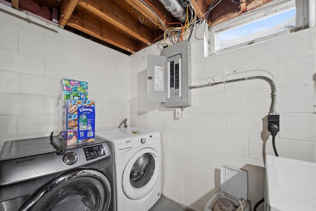 laundry area featuring washing machine and clothes dryer, laundry area, electric panel, and concrete block wall