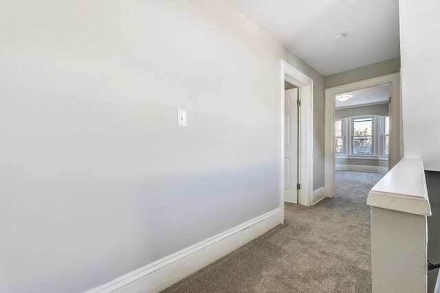 corridor featuring baseboards and carpet floors