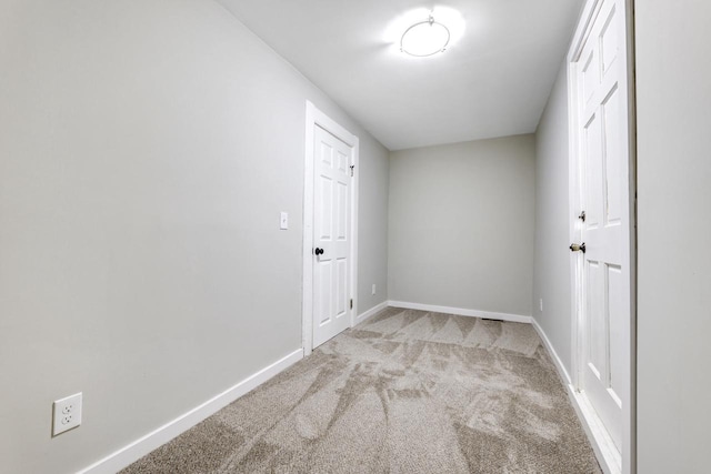 hallway featuring carpet floors and baseboards