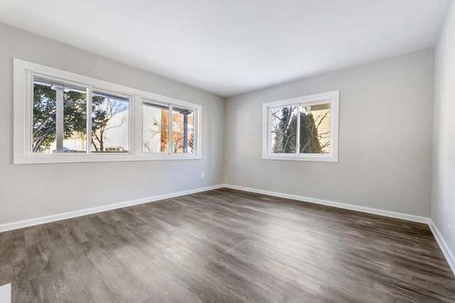 unfurnished room featuring a wealth of natural light, baseboards, and dark wood-type flooring