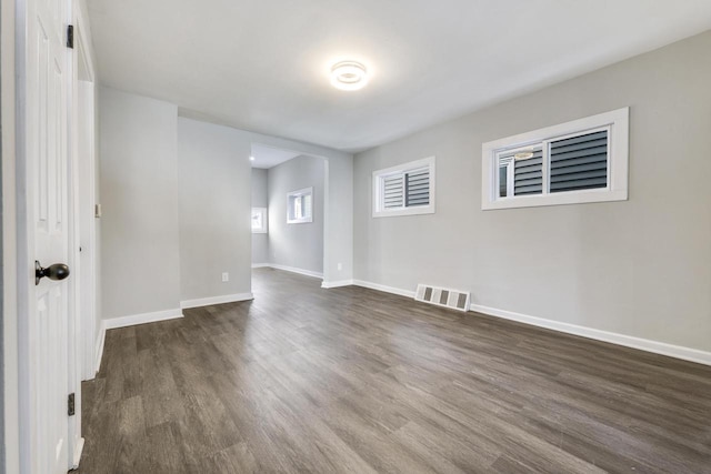 unfurnished room with dark wood-style flooring, baseboards, and visible vents