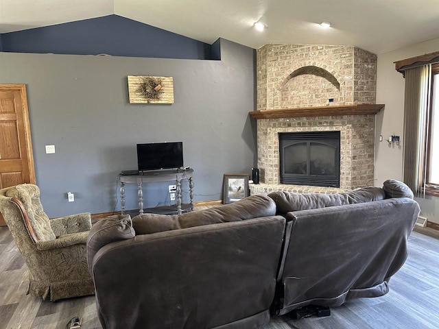 living room with vaulted ceiling, a brick fireplace, plenty of natural light, and wood finished floors