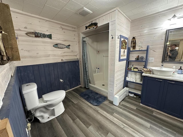 full bathroom with wood walls, toilet, wood finished floors, vanity, and a stall shower