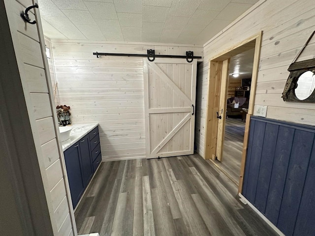 bar with wood walls, a barn door, and dark wood-style floors