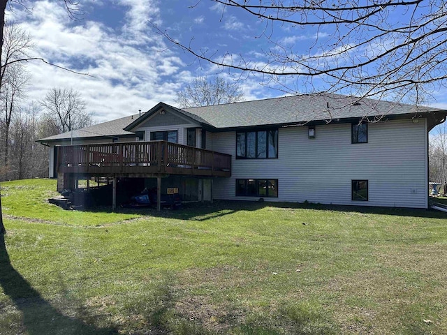 back of property featuring a wooden deck, a shingled roof, and a lawn