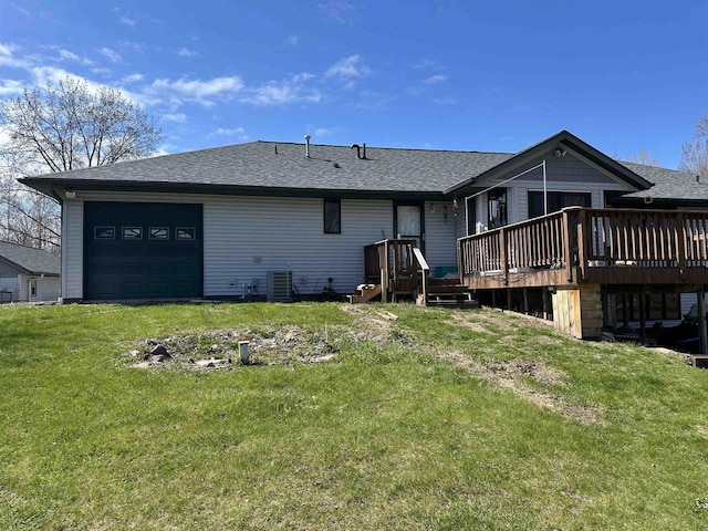 rear view of property featuring a lawn, a garage, central air condition unit, a deck, and roof with shingles