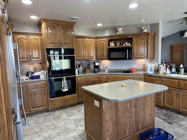 kitchen with brown cabinetry, a sink, a kitchen island, black appliances, and light countertops