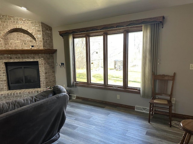 living room featuring baseboards, wood finished floors, lofted ceiling, and a fireplace