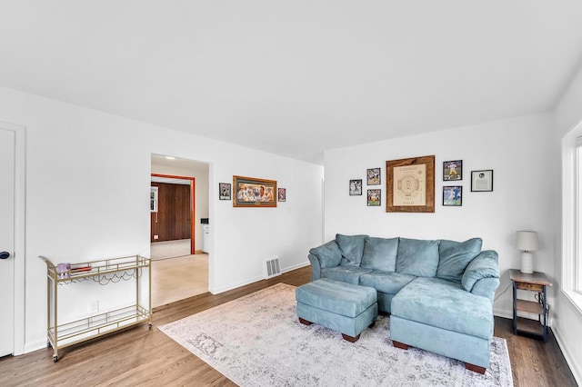 living room with baseboards, visible vents, and wood finished floors